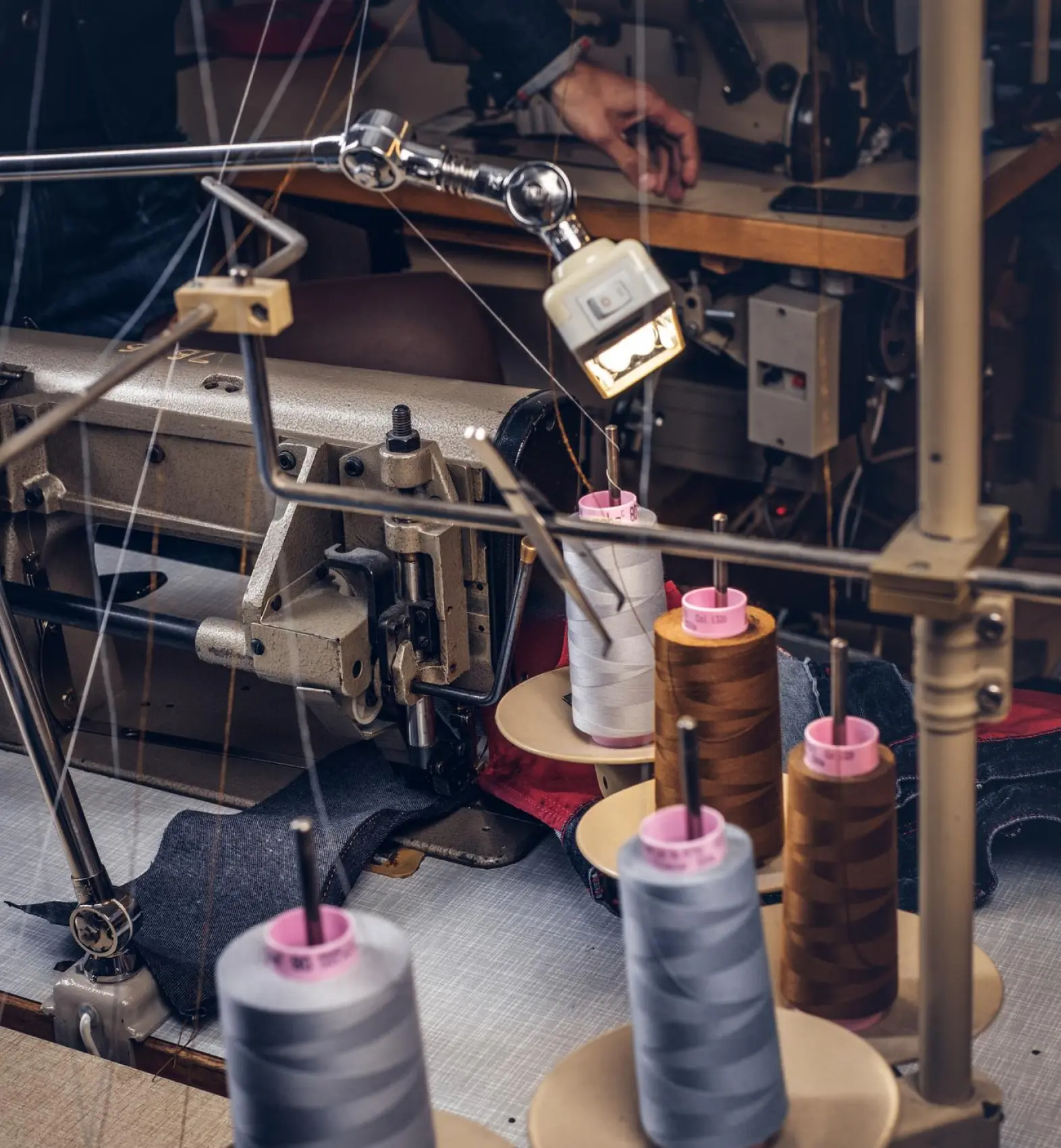 Industrial sewing machine with spools of thread at a Lux Industries factory