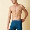 Male model wearing Lux Champion long trunk underwear in Air Force Blue, posing against a neutral beige studio background.